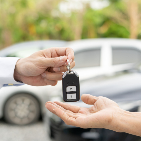 A person handing a set of new car keys to the purchaser