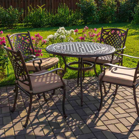 Outdoor furniture on a sunny patio surrounded by a bright green lawn