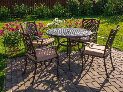 Outdoor furniture on a sunny patio surrounded by a bright green lawn