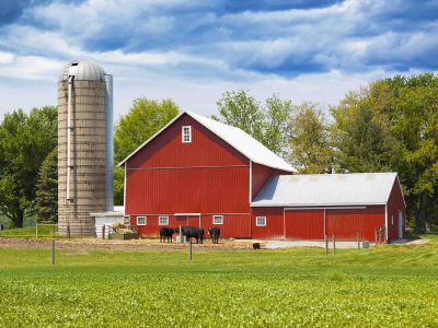 A red barn on a farm with a bright blue sky with white clouds in the background