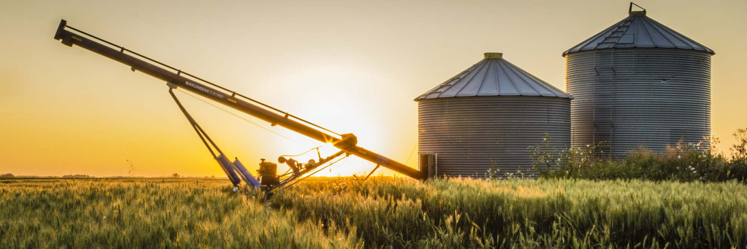 Pair of grain bins and an auger in the middle of a field